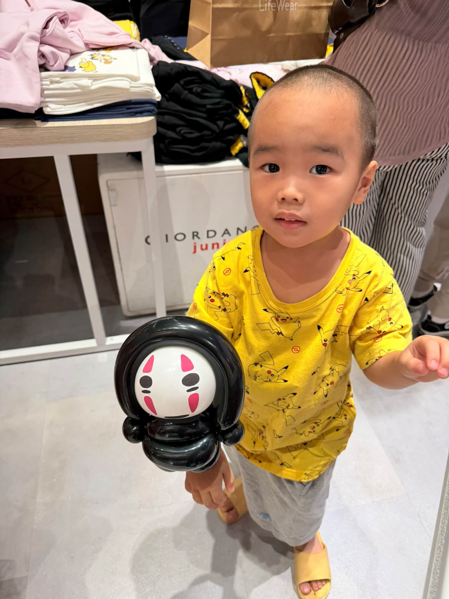 穿皮卡丘圖案黃色上衣的小男孩手拿黑色無臉男造型氣球