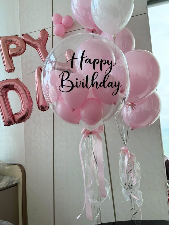 透明波波球裡塞滿粉色小氣球，印 Happy Birthday 字樣，下方垂著粉色與透明緞帶