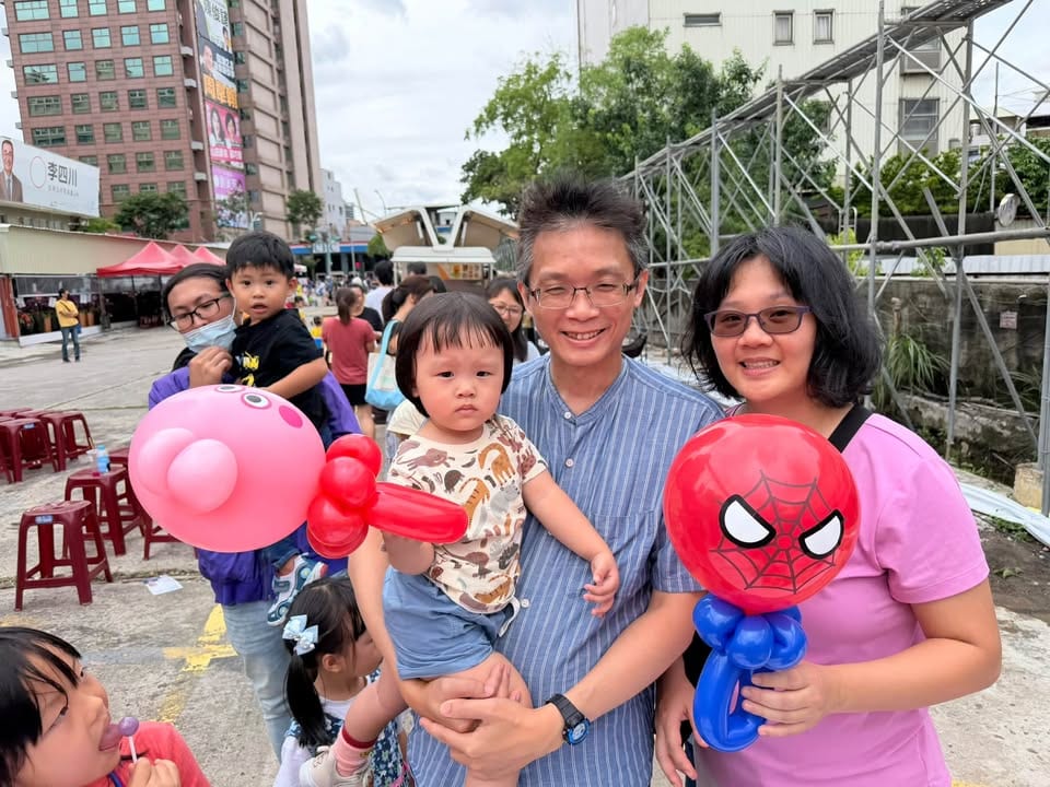 一家人拿著蜘蛛人和佩佩豬造型氣球合照，爸爸抱著小女孩