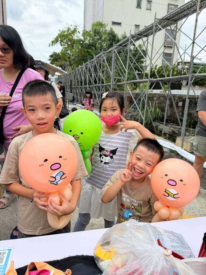 兩個男孩各抱一隻橘色的角落生物炸豬排造型氣球，後面的女孩拿著綠色鳥嘴造型氣球