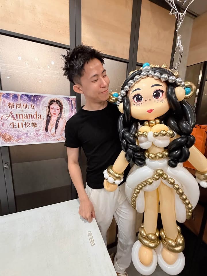 我抱著白金禮服人像氣球人偶，旁邊貼著生日快樂海報