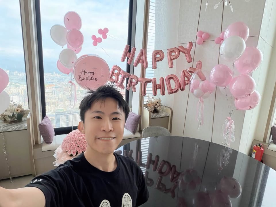 我在完成的粉色生日佈置前自拍，身後是玫瑰金字母氣球、粉白氣球束和粉色玫瑰花束