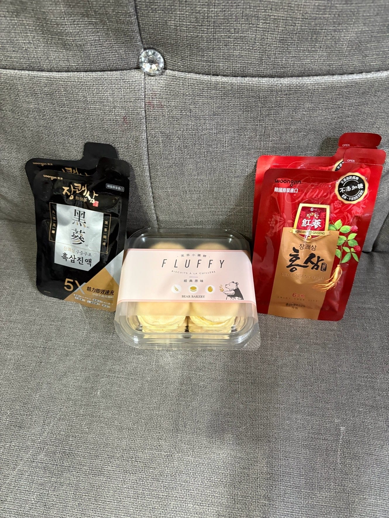 灰色沙發上擺著兩種韓國人蔘飲和一盒小圓餅