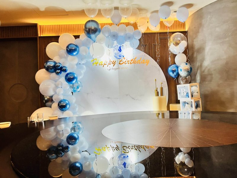黑色圓桌桌面倒映著藍白氣球拱與金色 Happy Birthday 大理石紋圓形背板