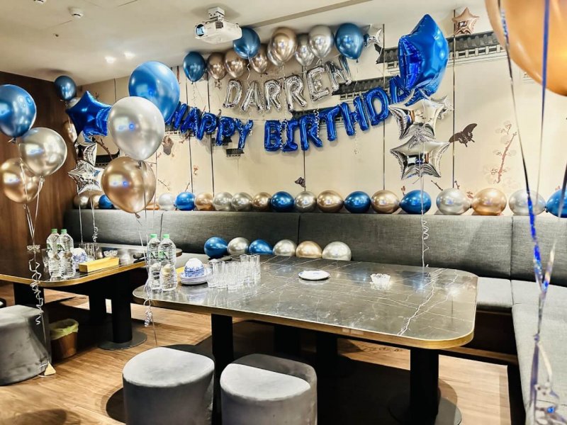 金屬藍色生日派對包廂全景,沙發牆掛藍色 HAPPY BIRTHDAY 與銀色名字字母氣球
