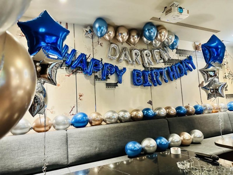 Darren 生日字母背牆兩側各掛寶藍與銀色星星鋁箔氣球,沙發椅背排滿藍銀金小氣球